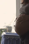 a pregnant woman holding her stomach in front of a window at 2Ls in Bowmanville. Prenatal Massage