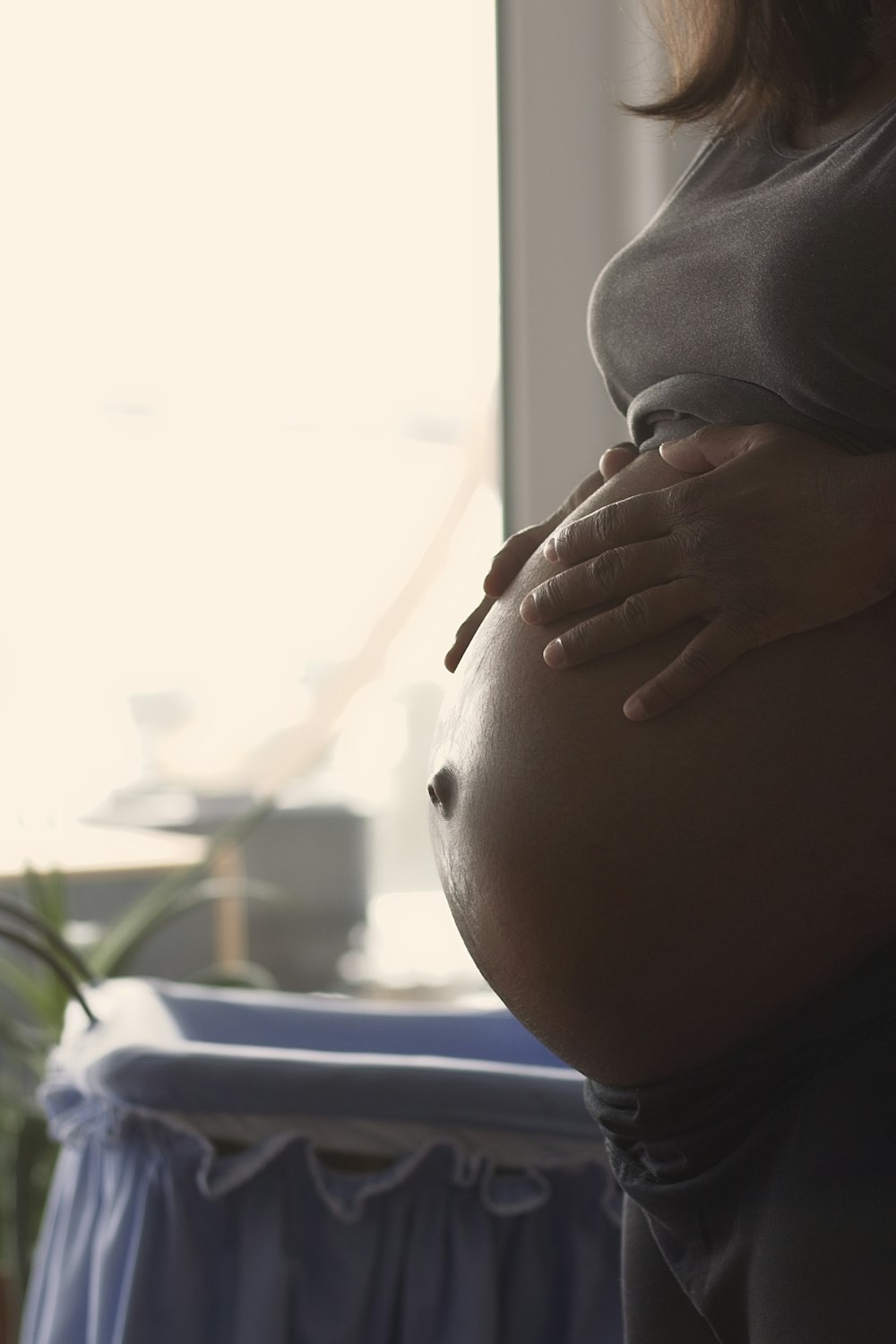 a pregnant woman holding her stomach in front of a window