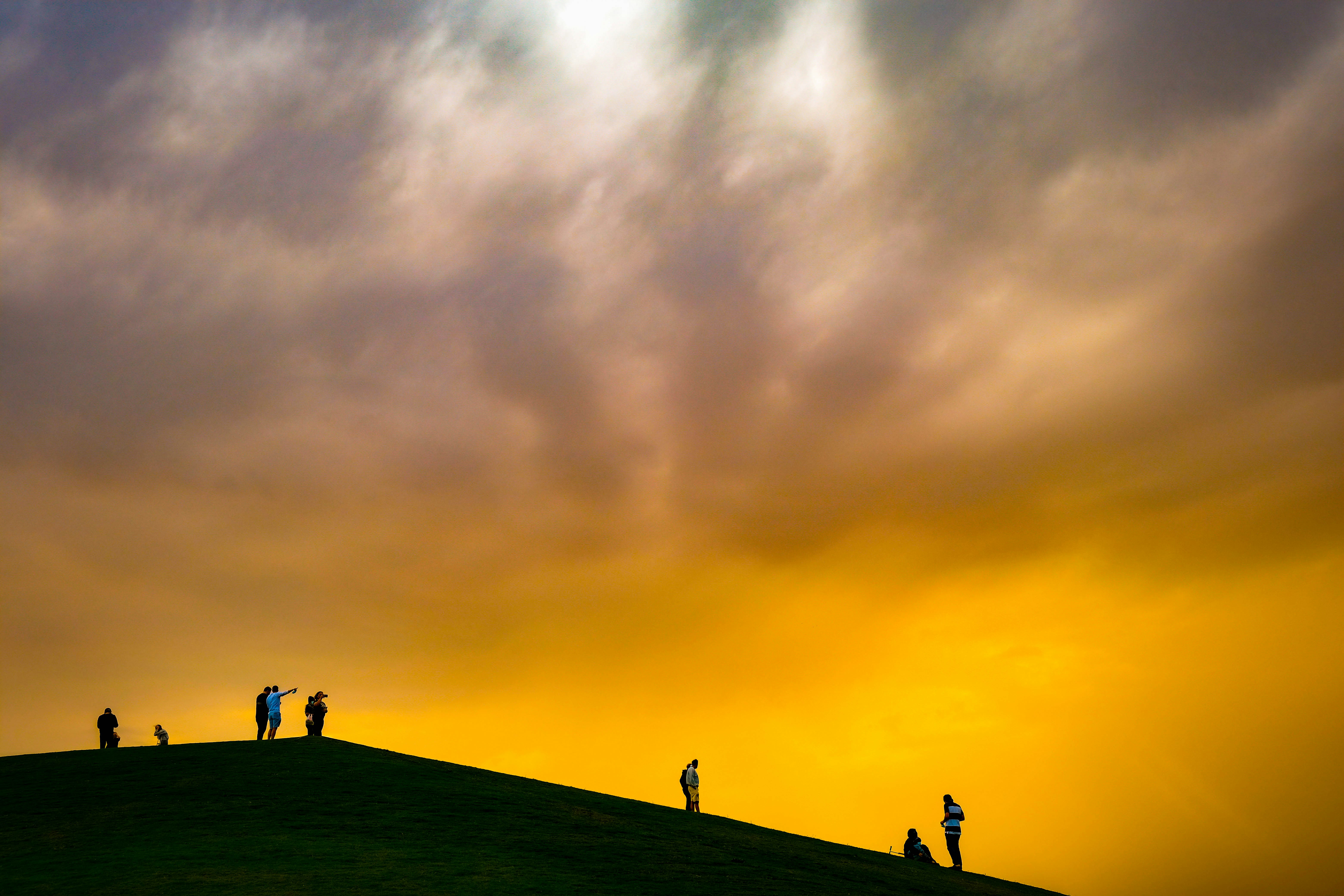 A group of people standing on top of a grass covered hill photo – Free ...