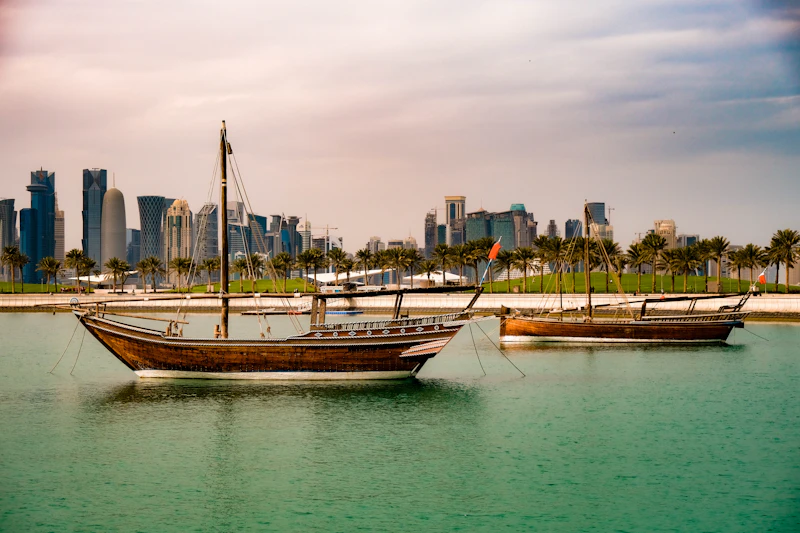 Traditional wooden boats moored in front of the Doha skyline in Qatar