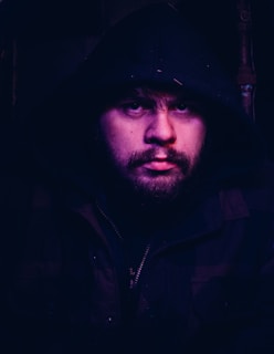 A moody close-up of a model wearing a neon-lit oversized hoodie, shadows casting sharp angles on their face.