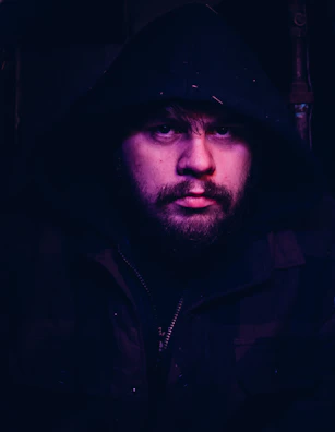 Close-up of a matte black oversized hoodie with chrome zipper details under moody lighting.