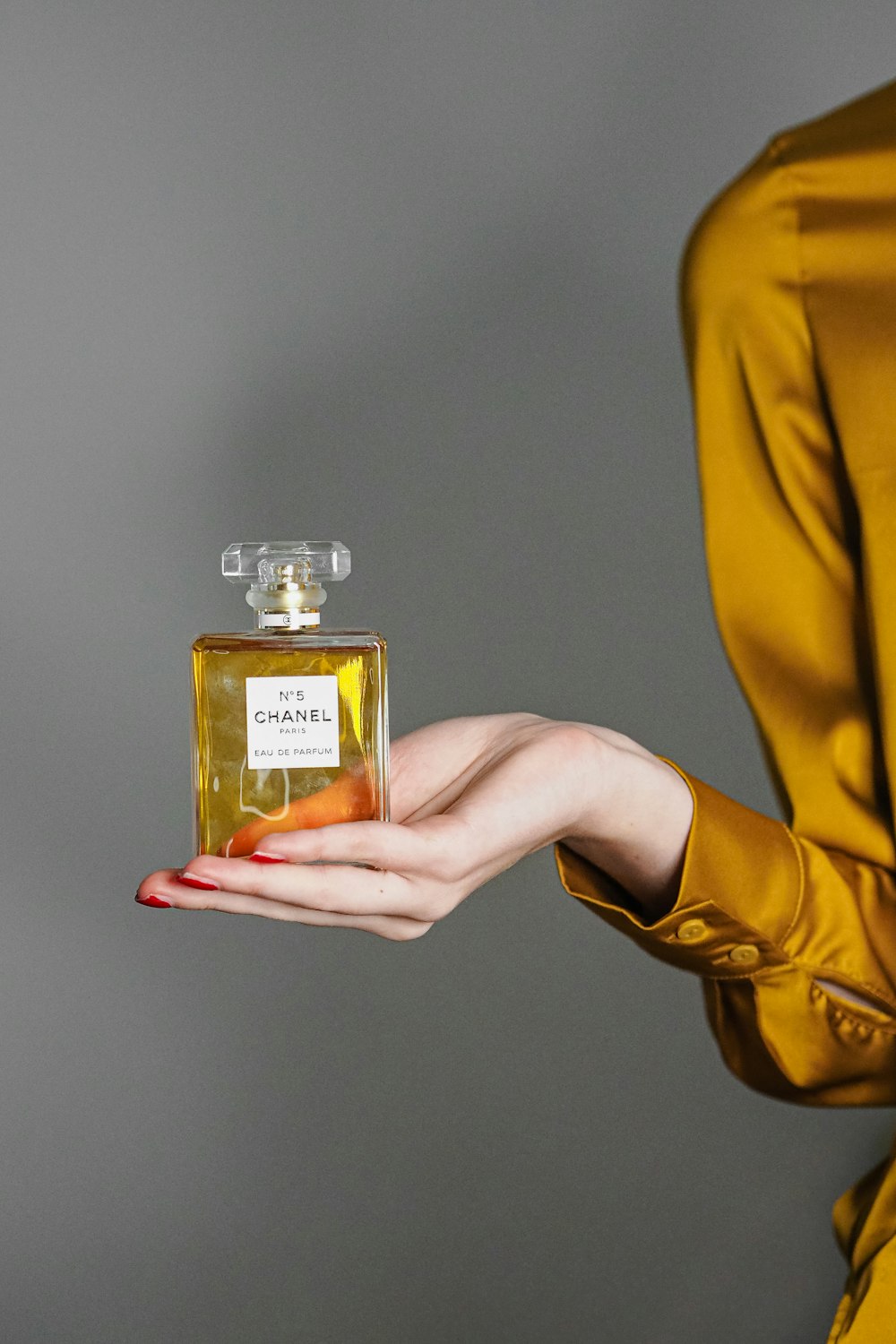 Una mujer sosteniendo una pequeña botella de perfume
