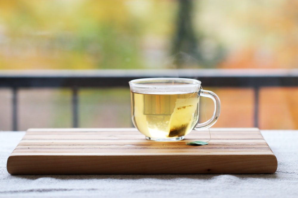 a cup of tea sitting on top of a wooden cutting board