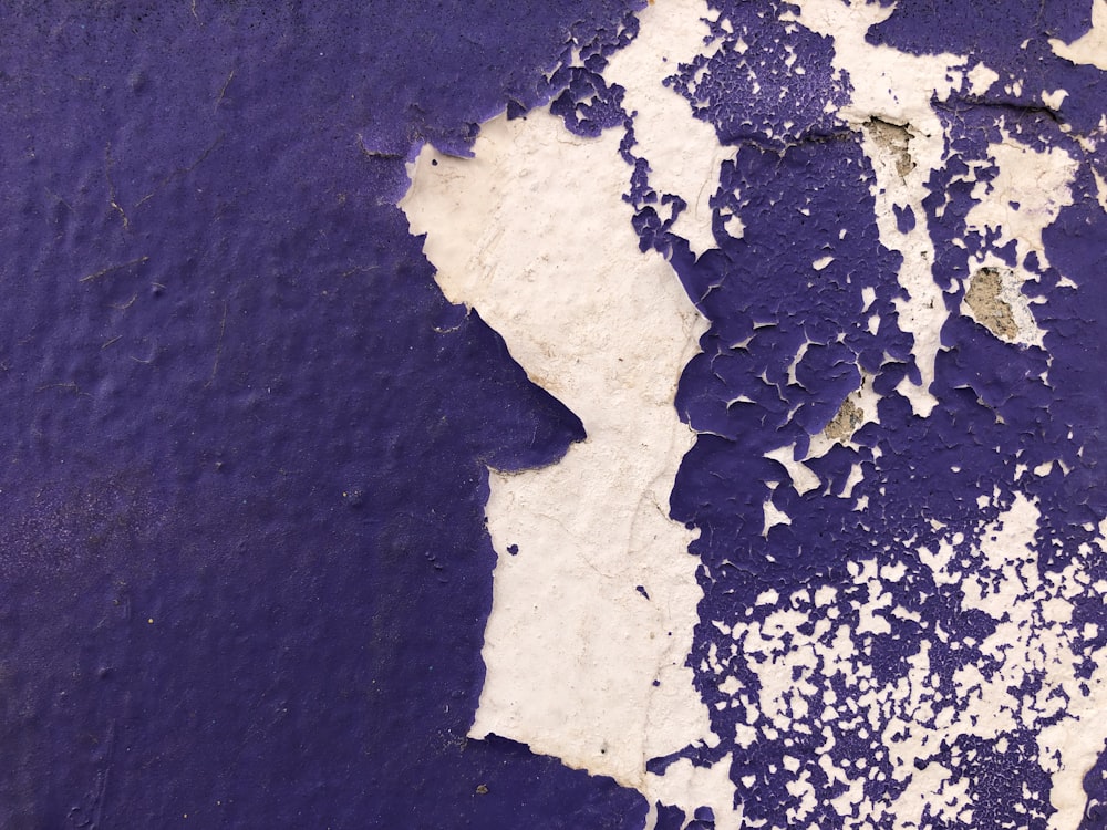 a purple and white wall with peeling paint