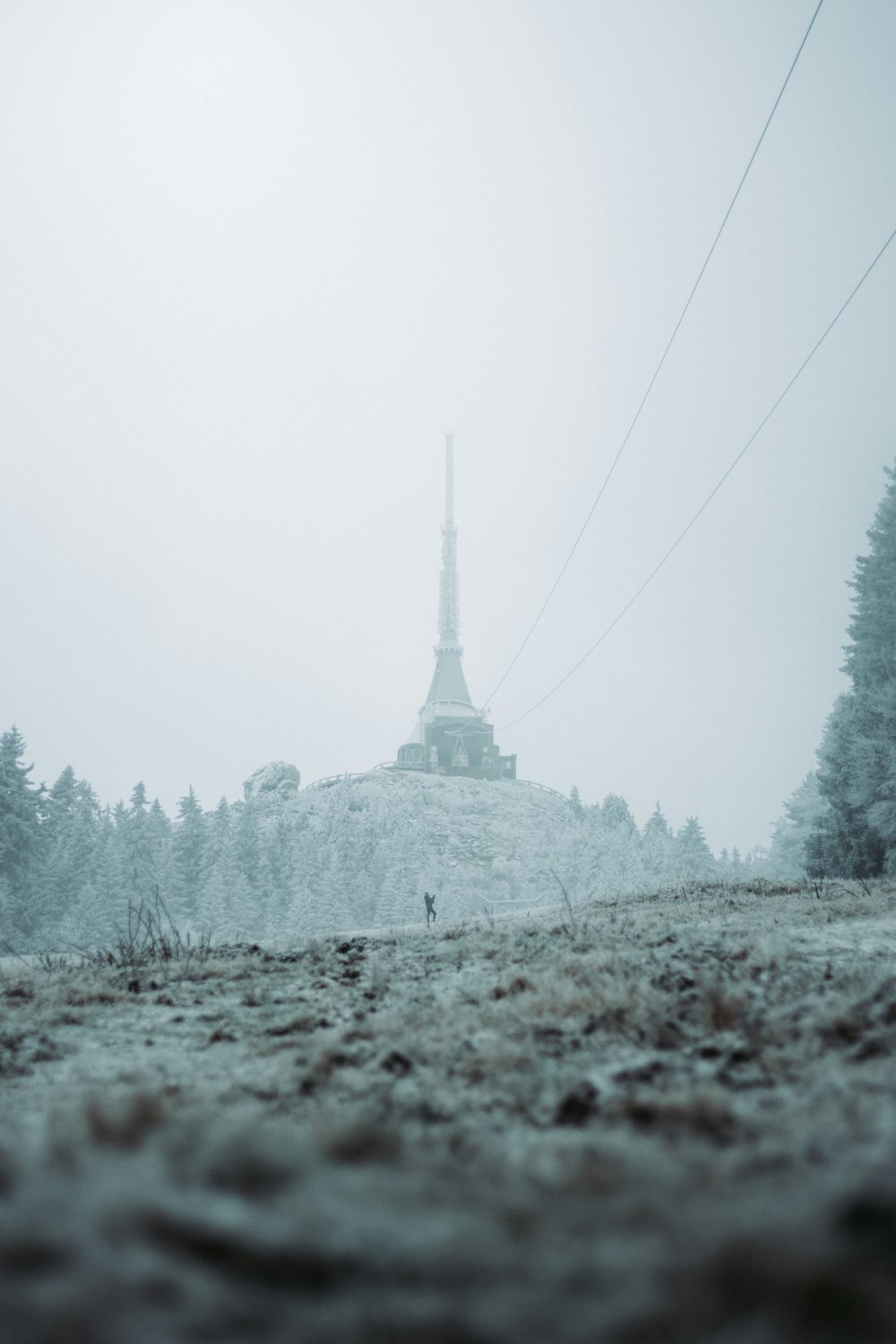 a hill covered in snow with a tower in the background