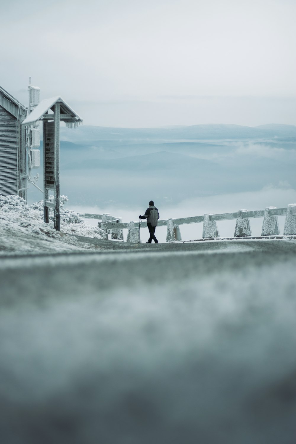 a man walking down a snow covered road next to a building