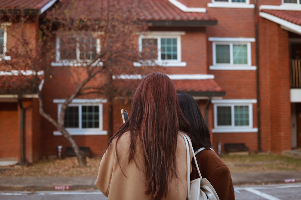 two women walking in front of a red brick building