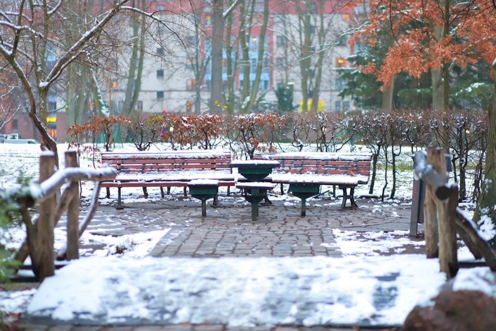 a snow covered park with benches and tables