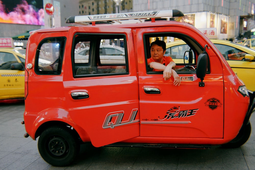 a man sitting in the driver's seat of a small car