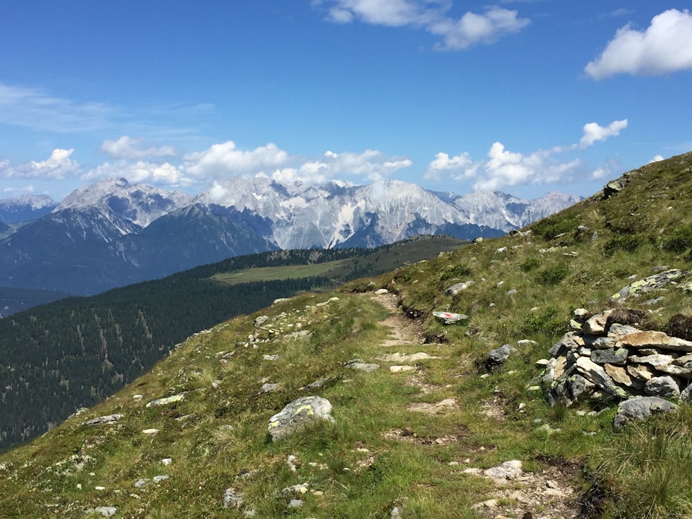 a trail on the side of a mountain with mountains in the background