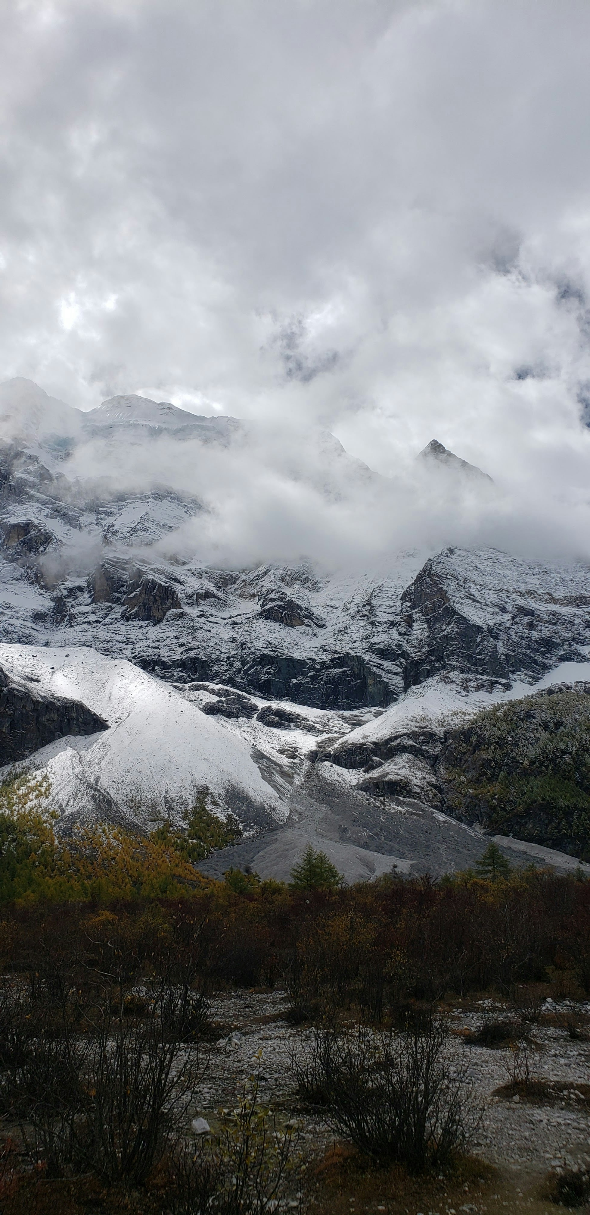 a snow covered mountain range under a cloudy sky