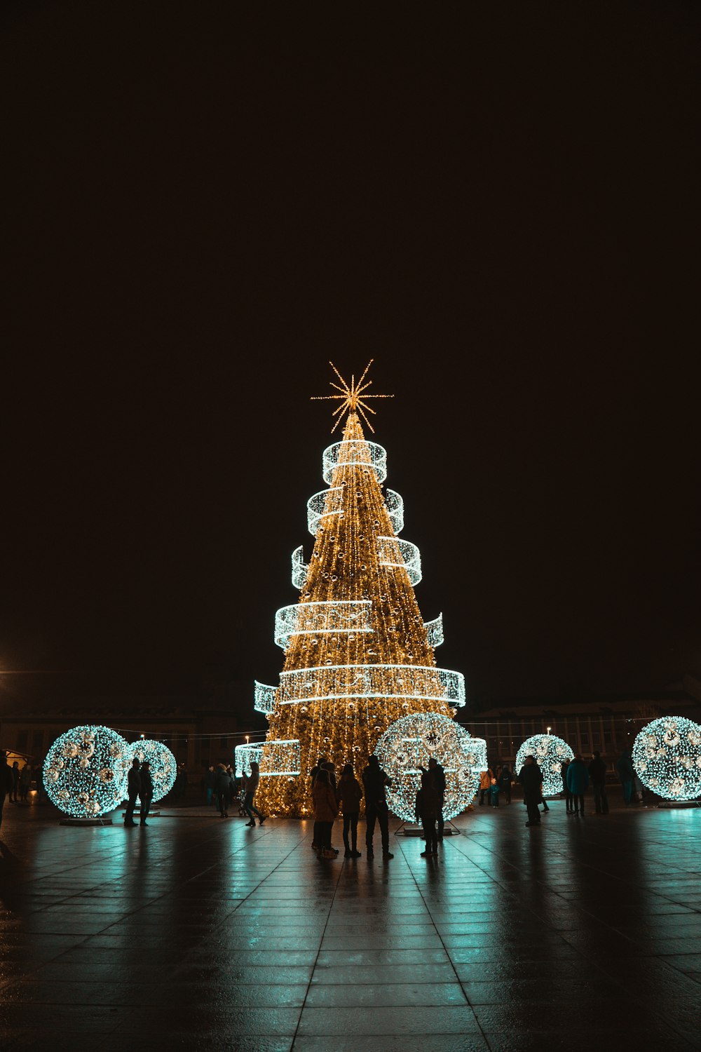 a lighted christmas tree with people standing around it