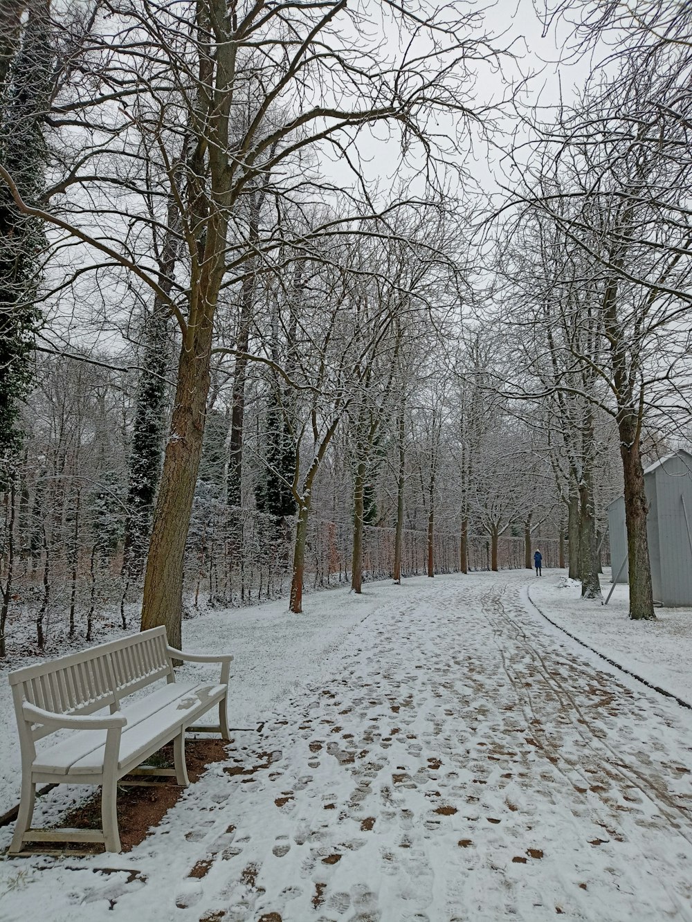 a white bench sitting in the middle of a snow covered park