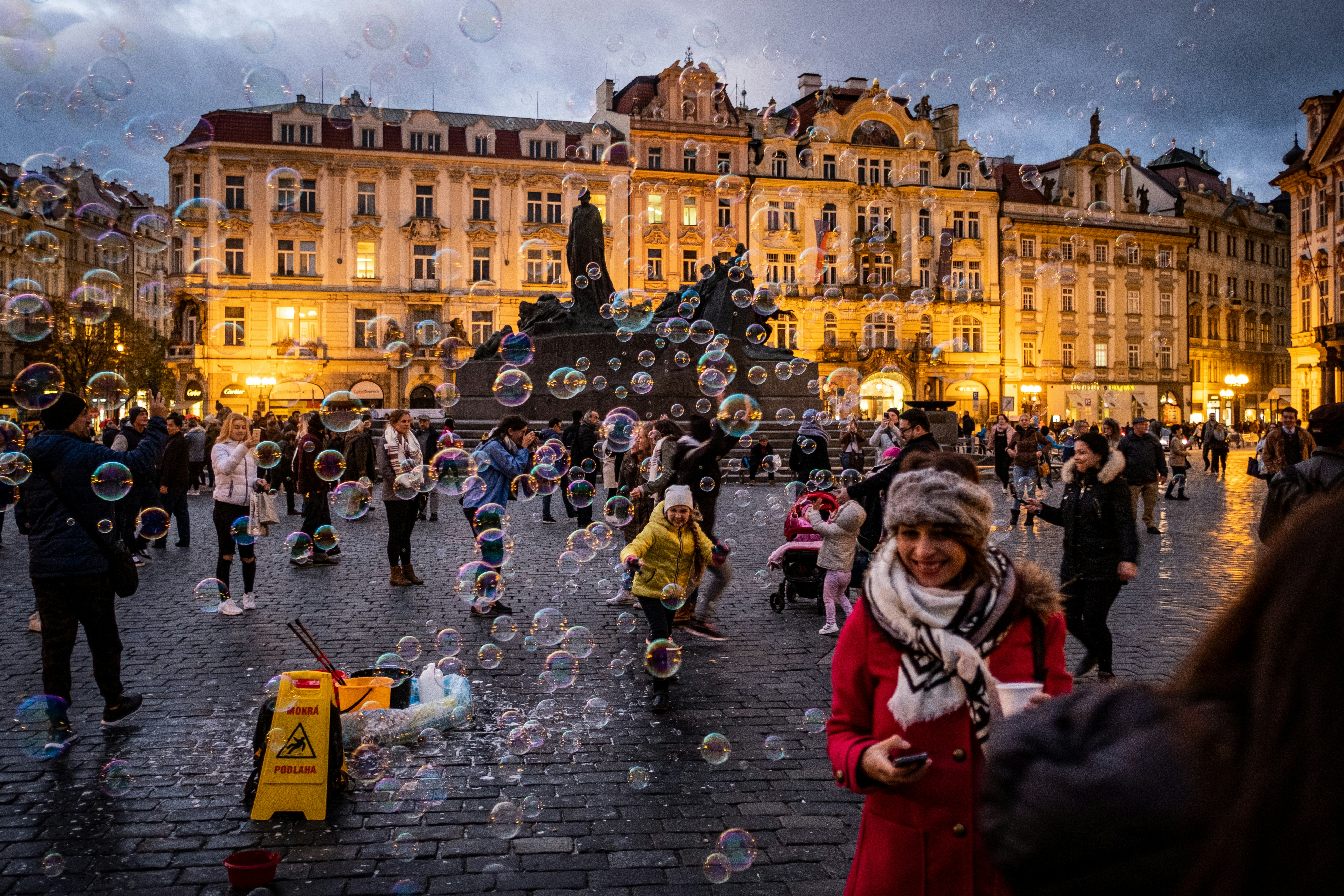 a group of people standing on a street next to a fountain, 