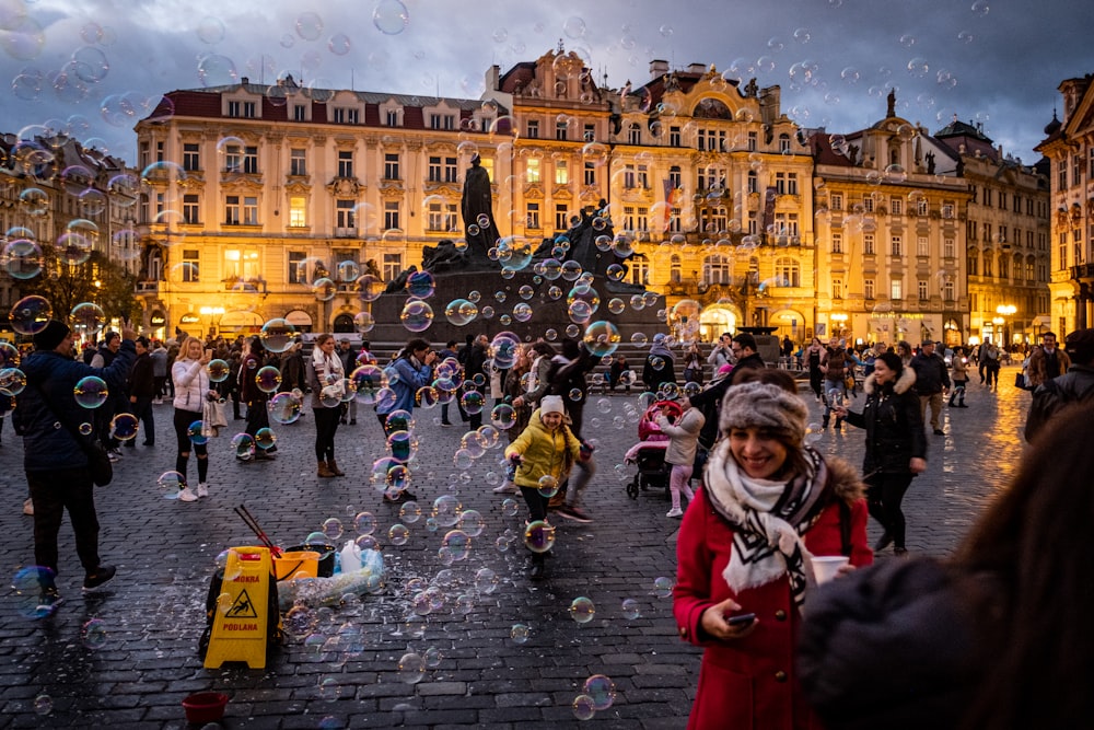 a group of people standing on a street next to a fountain