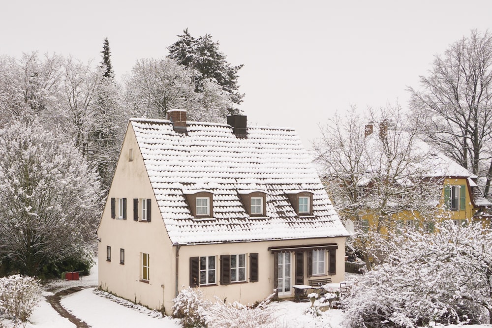 a house covered in snow next to trees