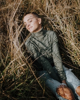 a young boy sitting in a field of tall grass