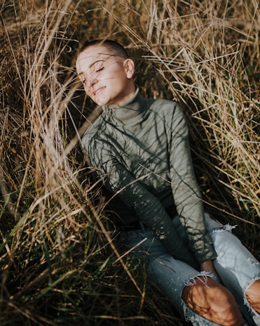 a young boy sitting in a field of tall grass