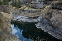 a rope bridge over a river in a canyon