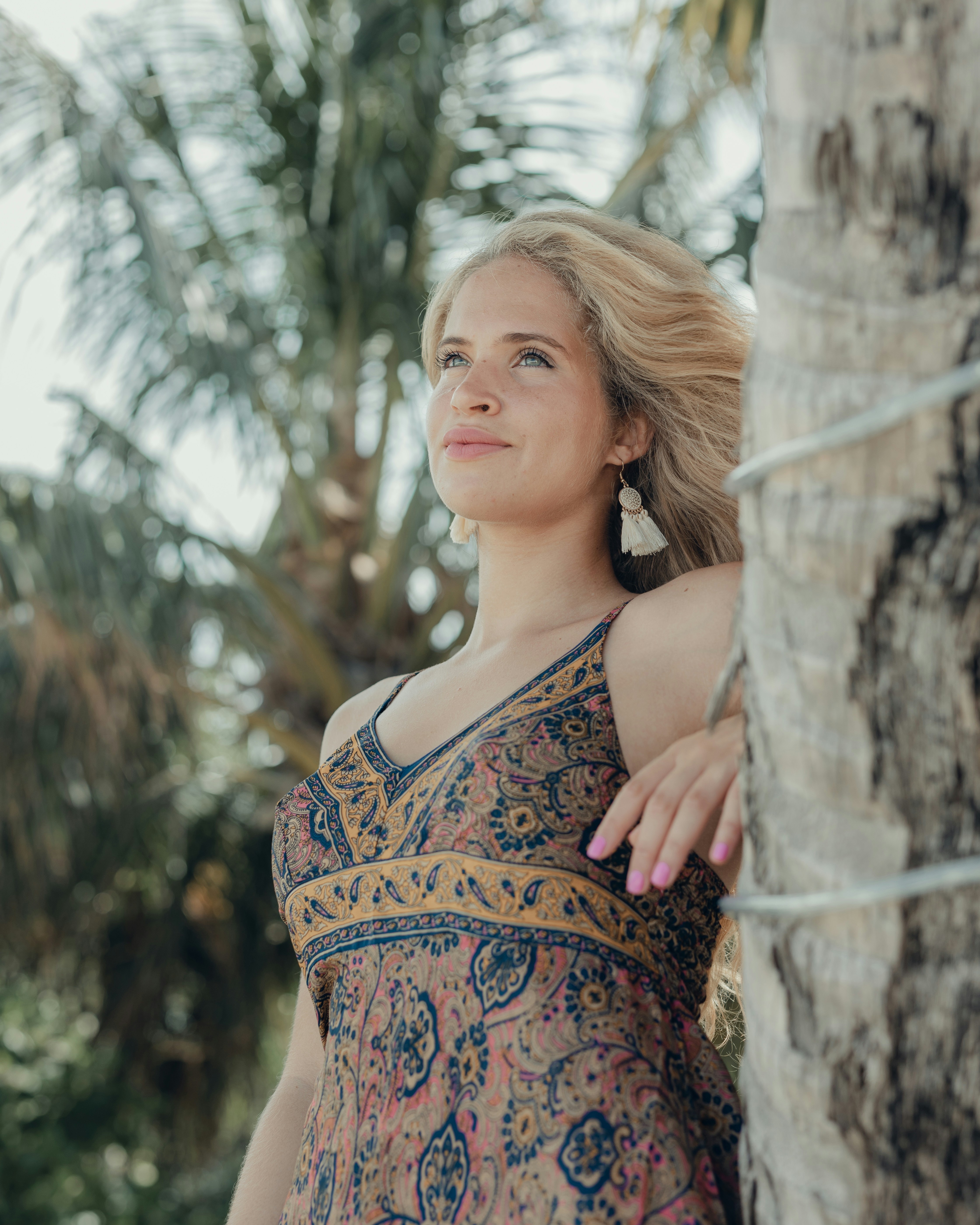 a woman standing next to a palm tree