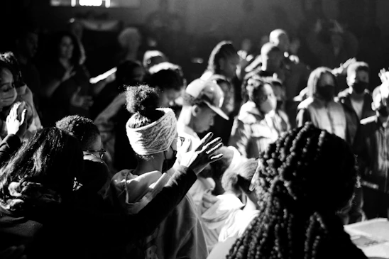A vibrant worship scene bathed in red and black lighting with the congregation united in praise.
