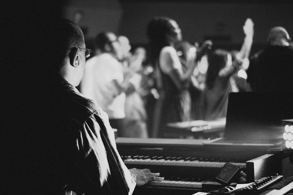 a man sitting at a piano in front of a crowd of people