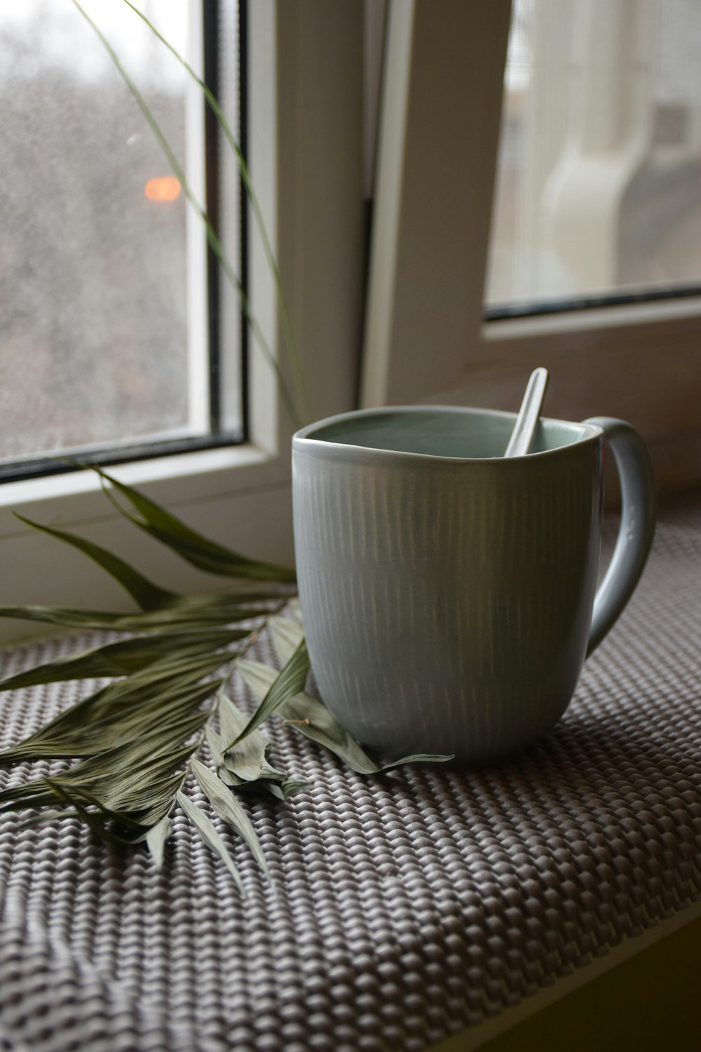 a cup with a spoon in it sitting on a window sill