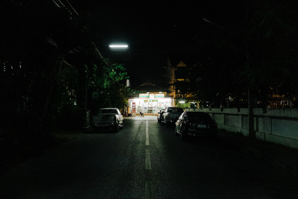 a street at night with cars parked on the side of the road