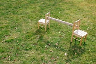 a couple of wooden chairs sitting on top of a lush green field