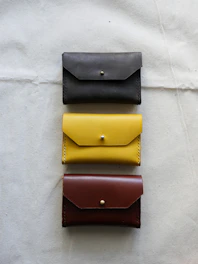 A selection of handmade leather wallets in warm brown tones displayed on a rustic fabric.