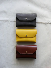 A selection of handmade leather wallets in warm brown tones displayed on a rustic fabric.