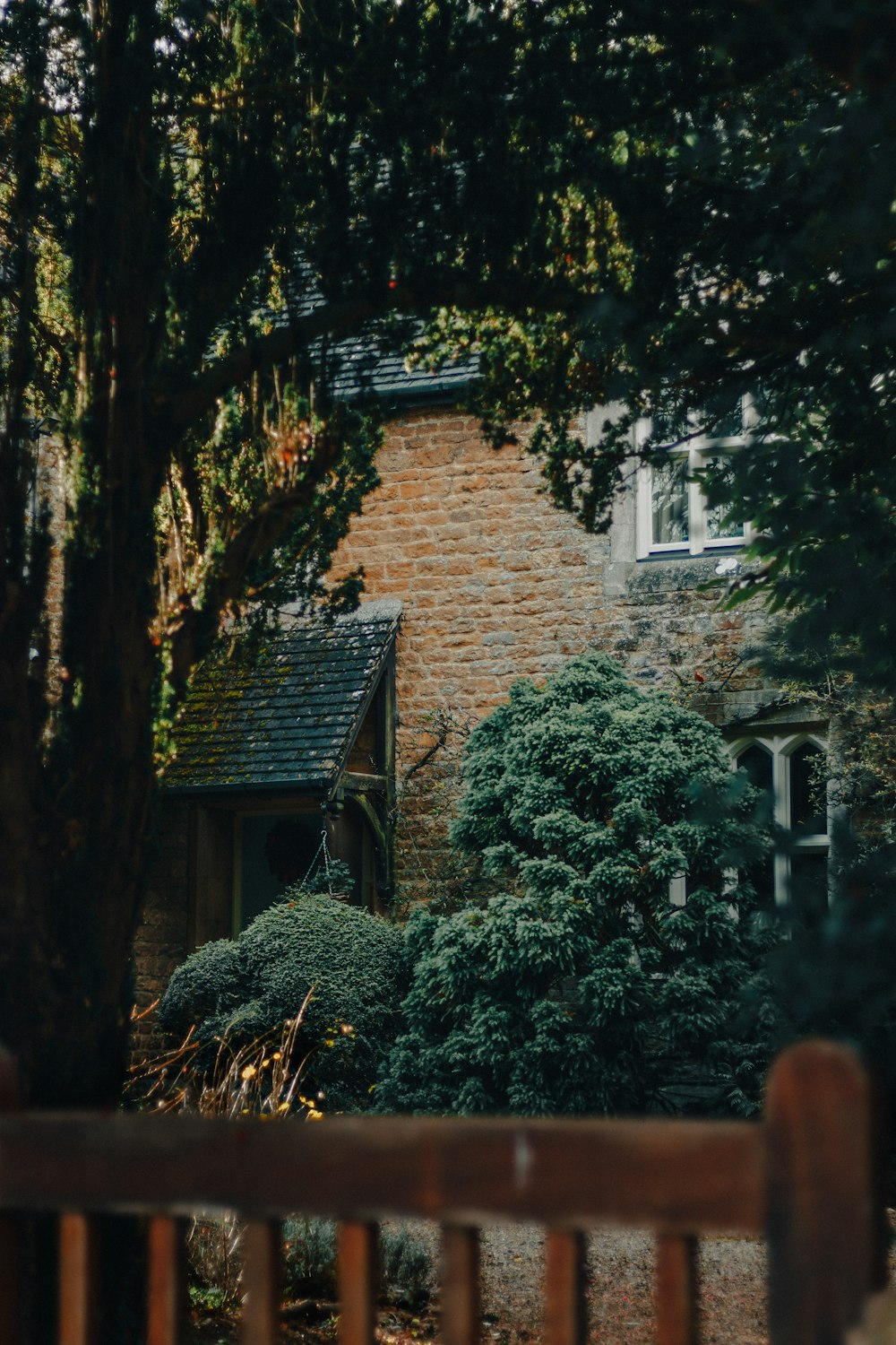 a brick house surrounded by trees and bushes