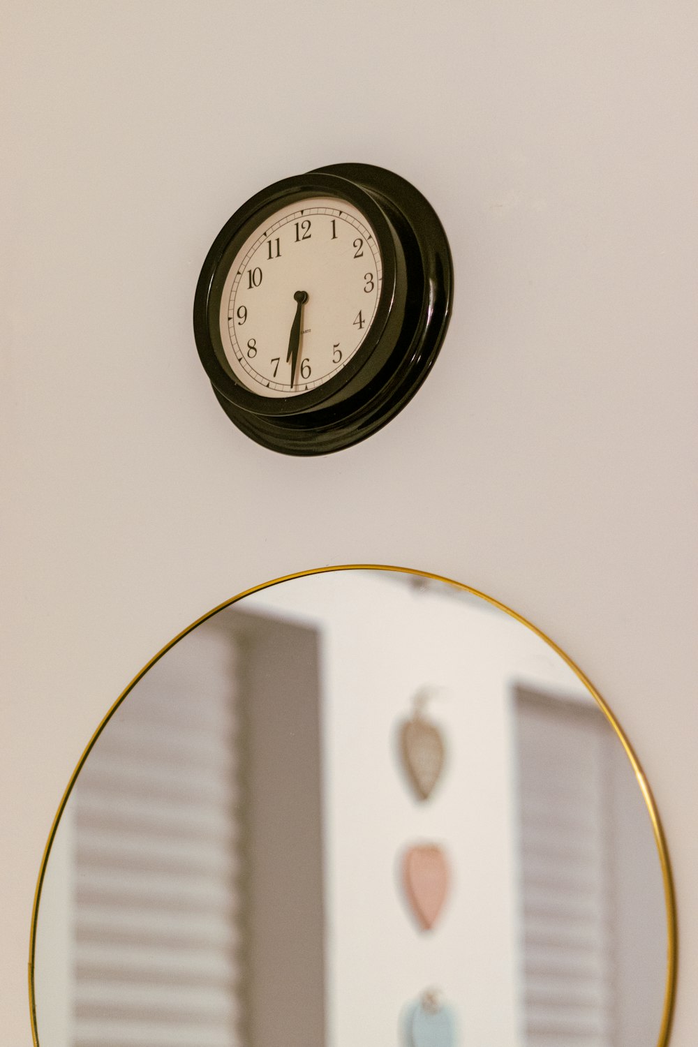 eine Uhr an der Wand über einem Spiegel