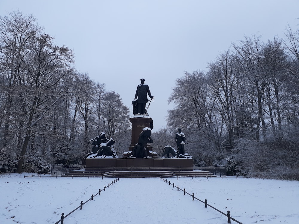 a statue in the middle of a snowy park