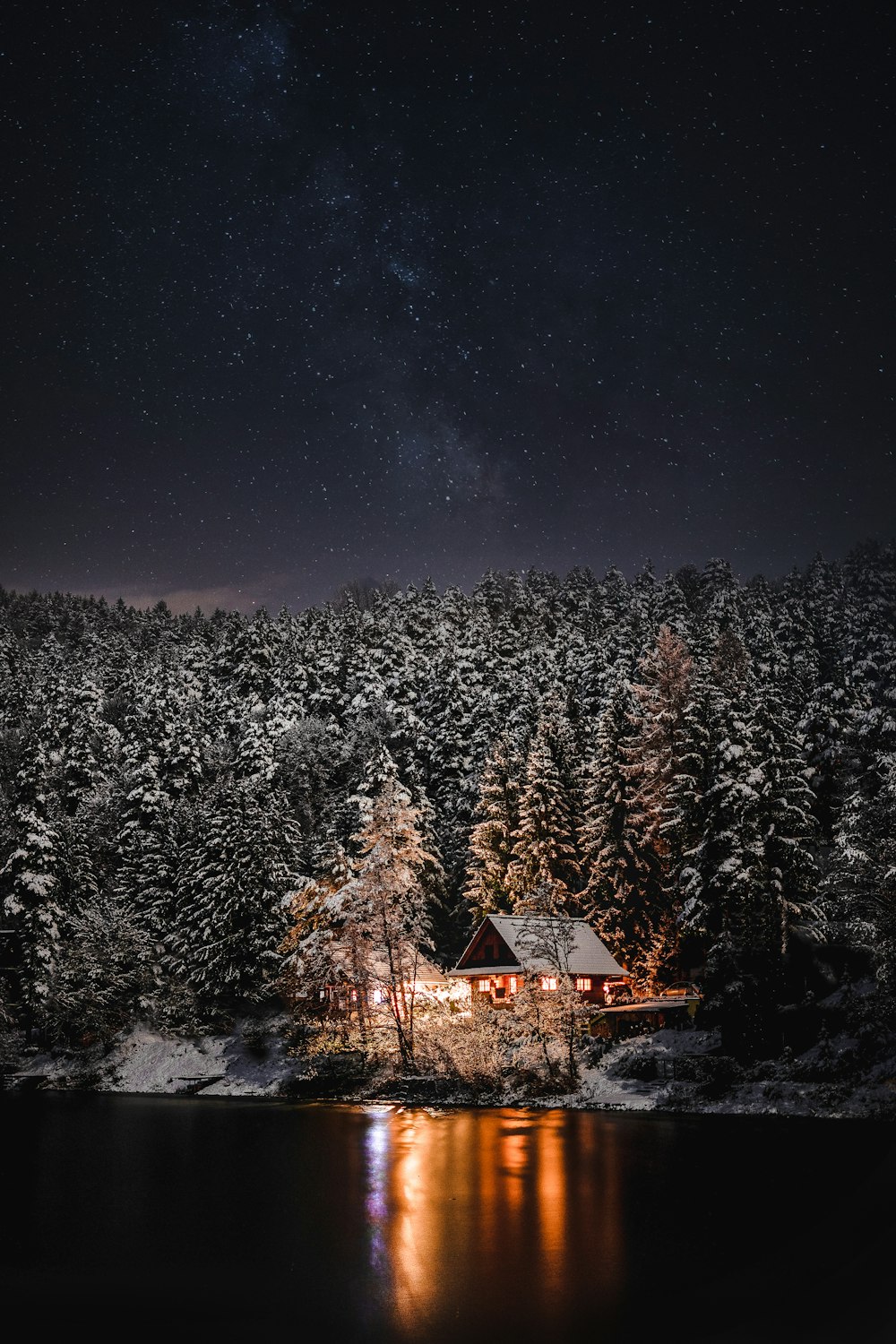 a cabin in the woods at night with the stars in the sky