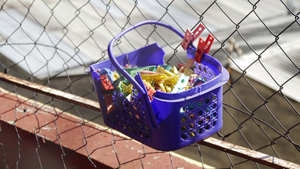 a blue basket filled with candy sitting on top of a fence