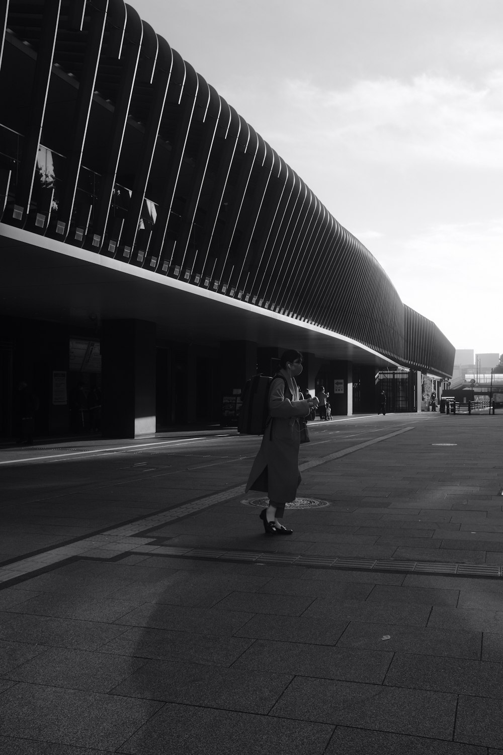 a woman walking down a street next to a tall building