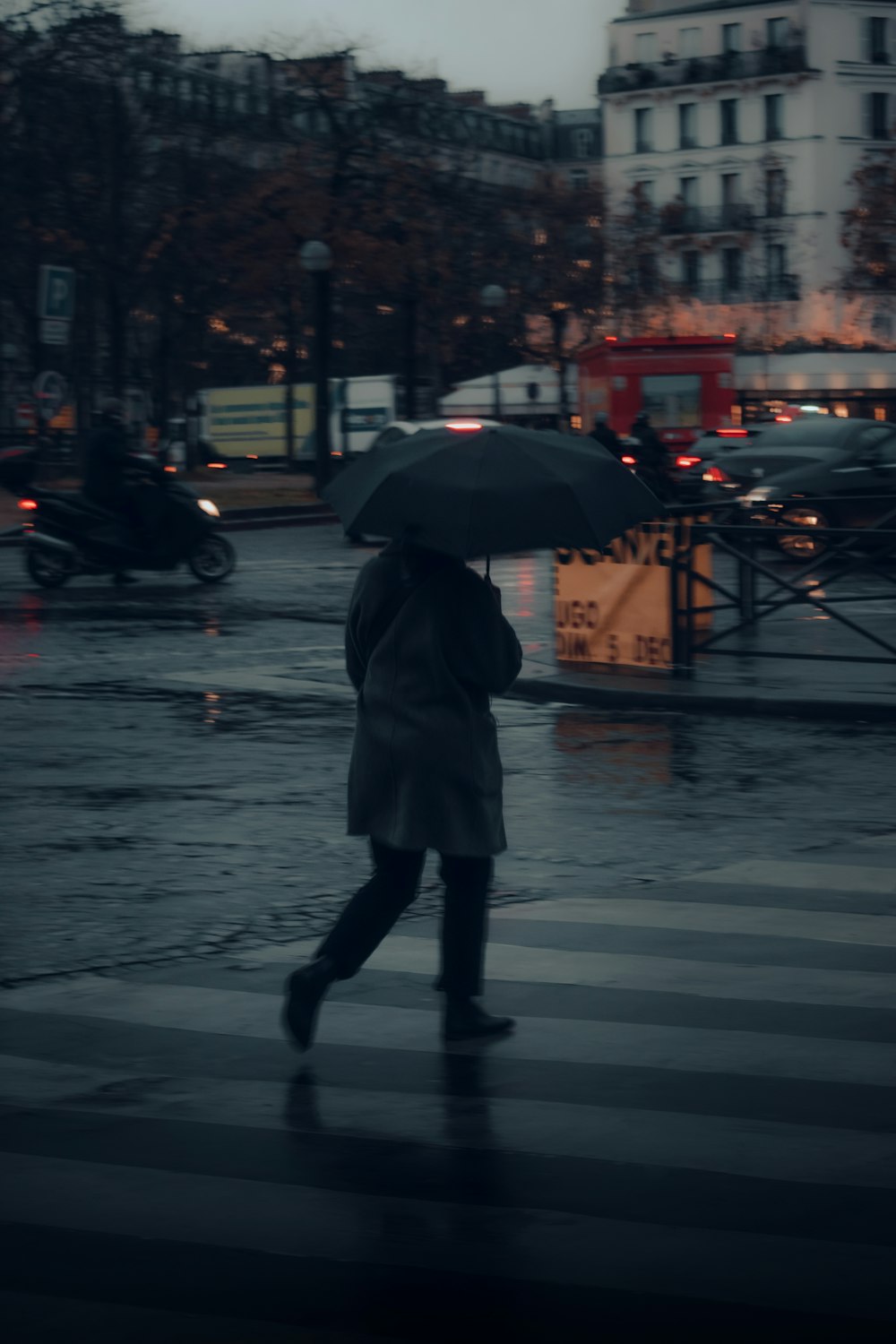 a woman walking across a street holding an umbrella