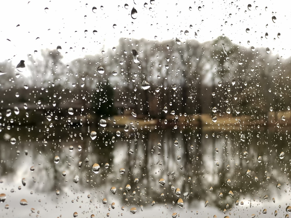 a view of a lake through a rain covered window