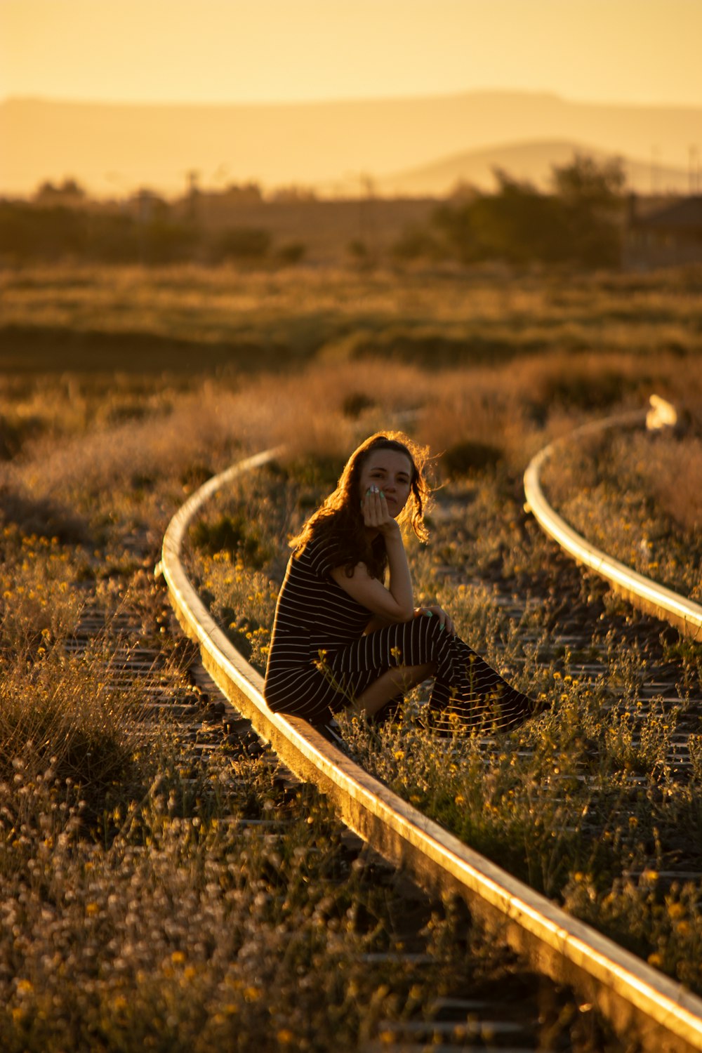 a woman sitting on a train track talking on a cell phone