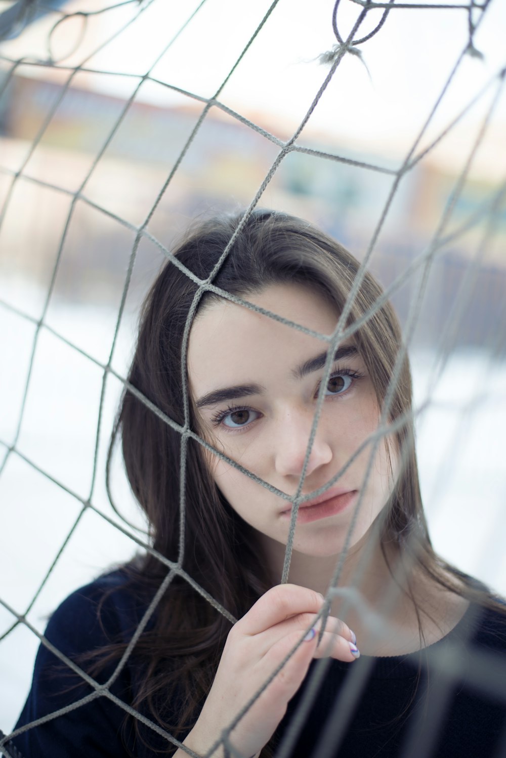 a woman standing behind a net looking at the camera