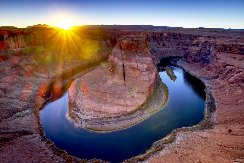 the sun is setting over a river in the desert