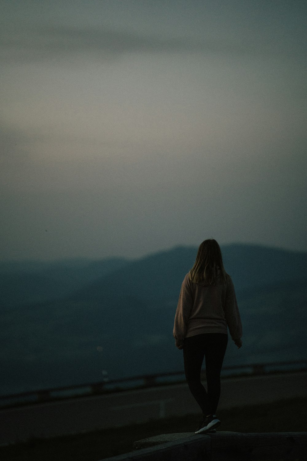 a woman standing on top of a hill looking at the sky