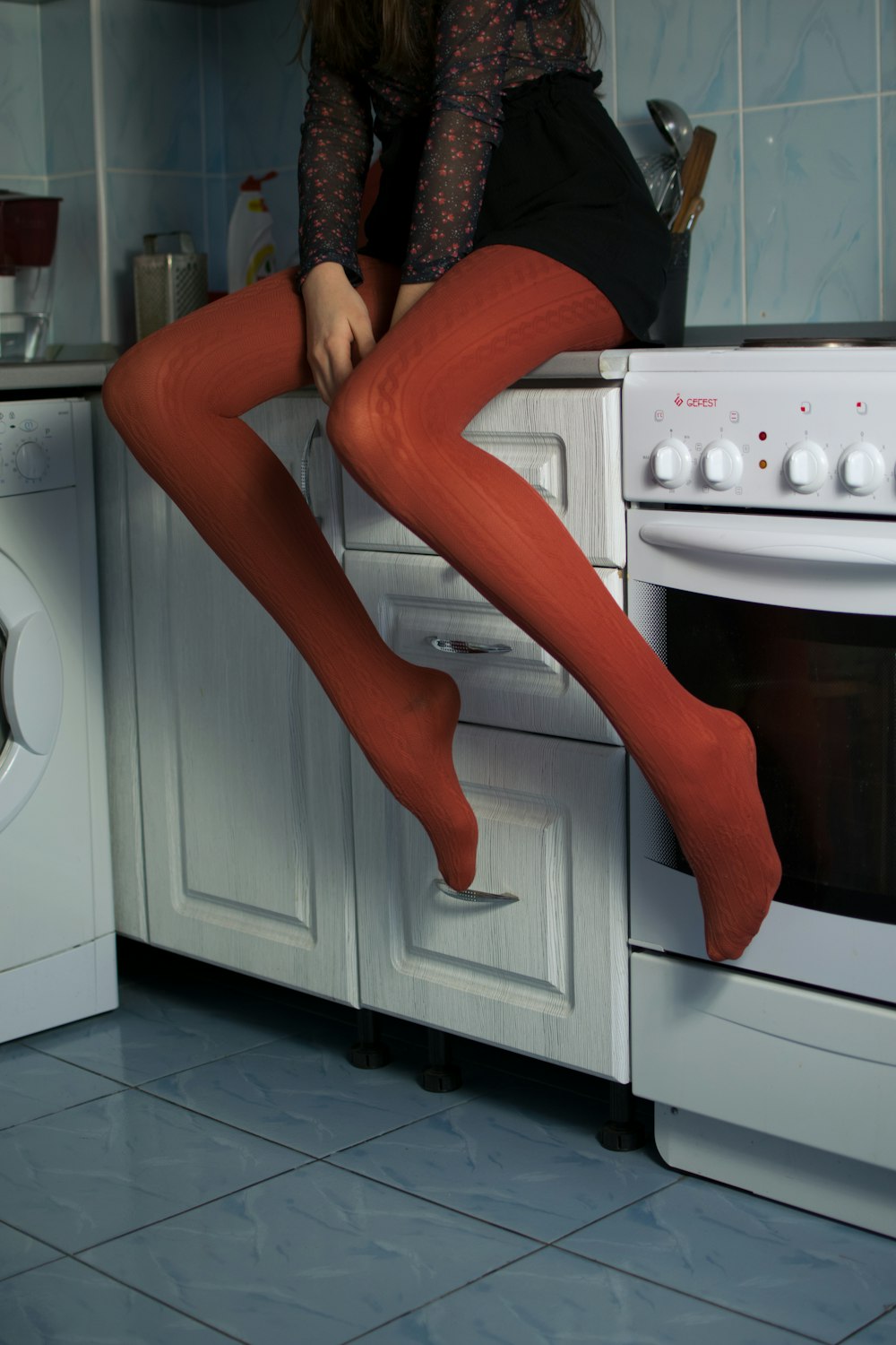 a woman in tights is sitting on a stove