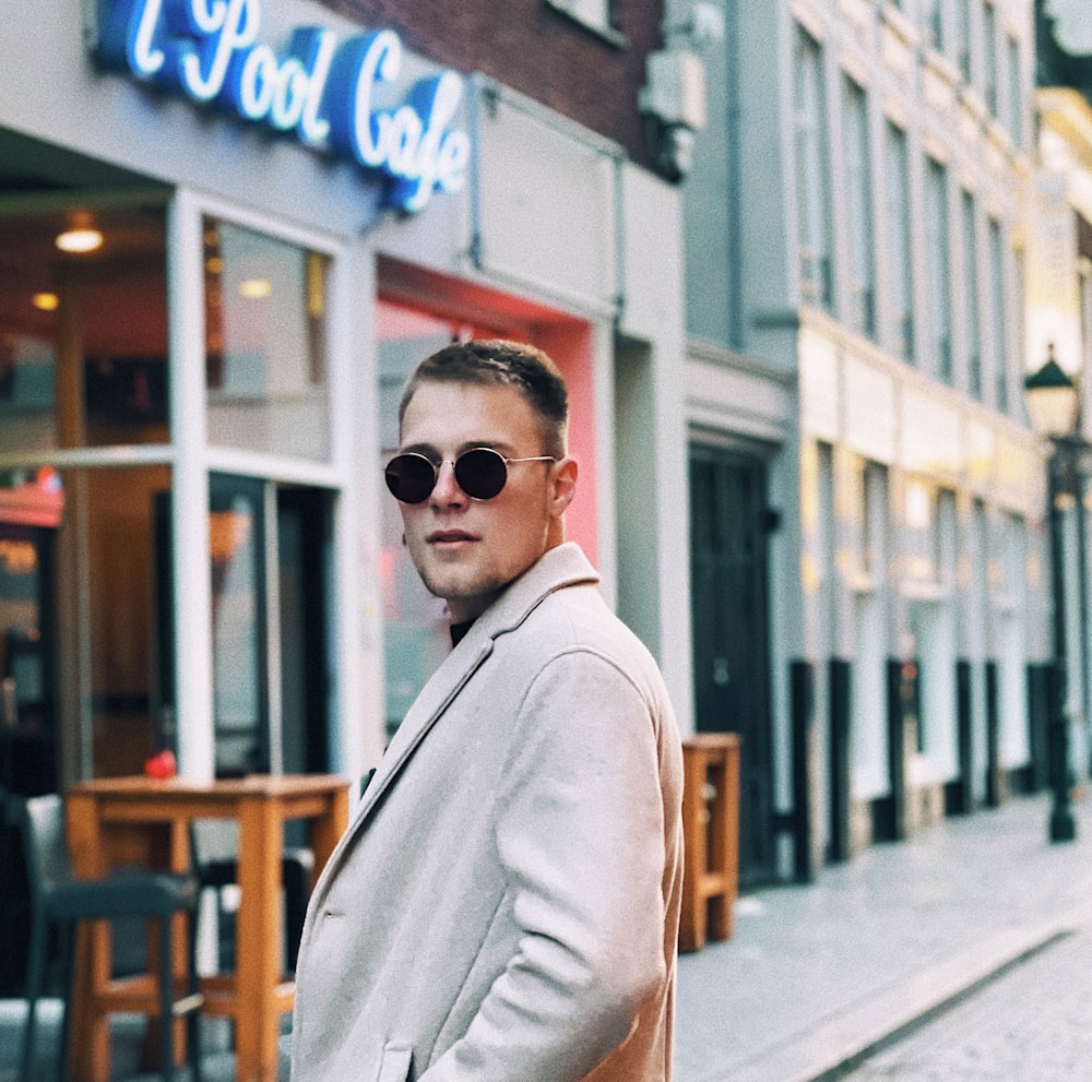 a man wearing sunglasses standing in front of a restaurant