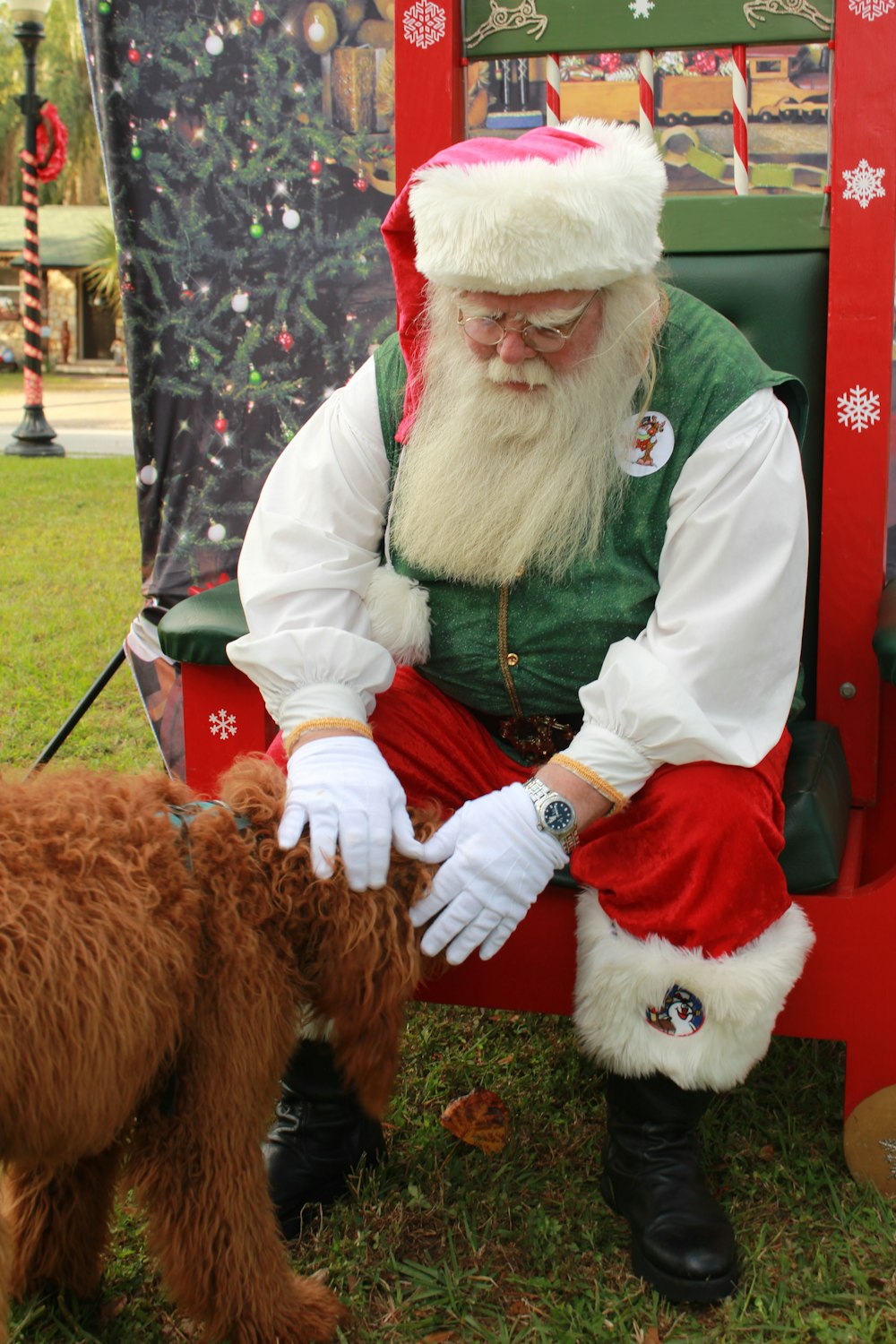 a man dressed as santa claus petting a dog