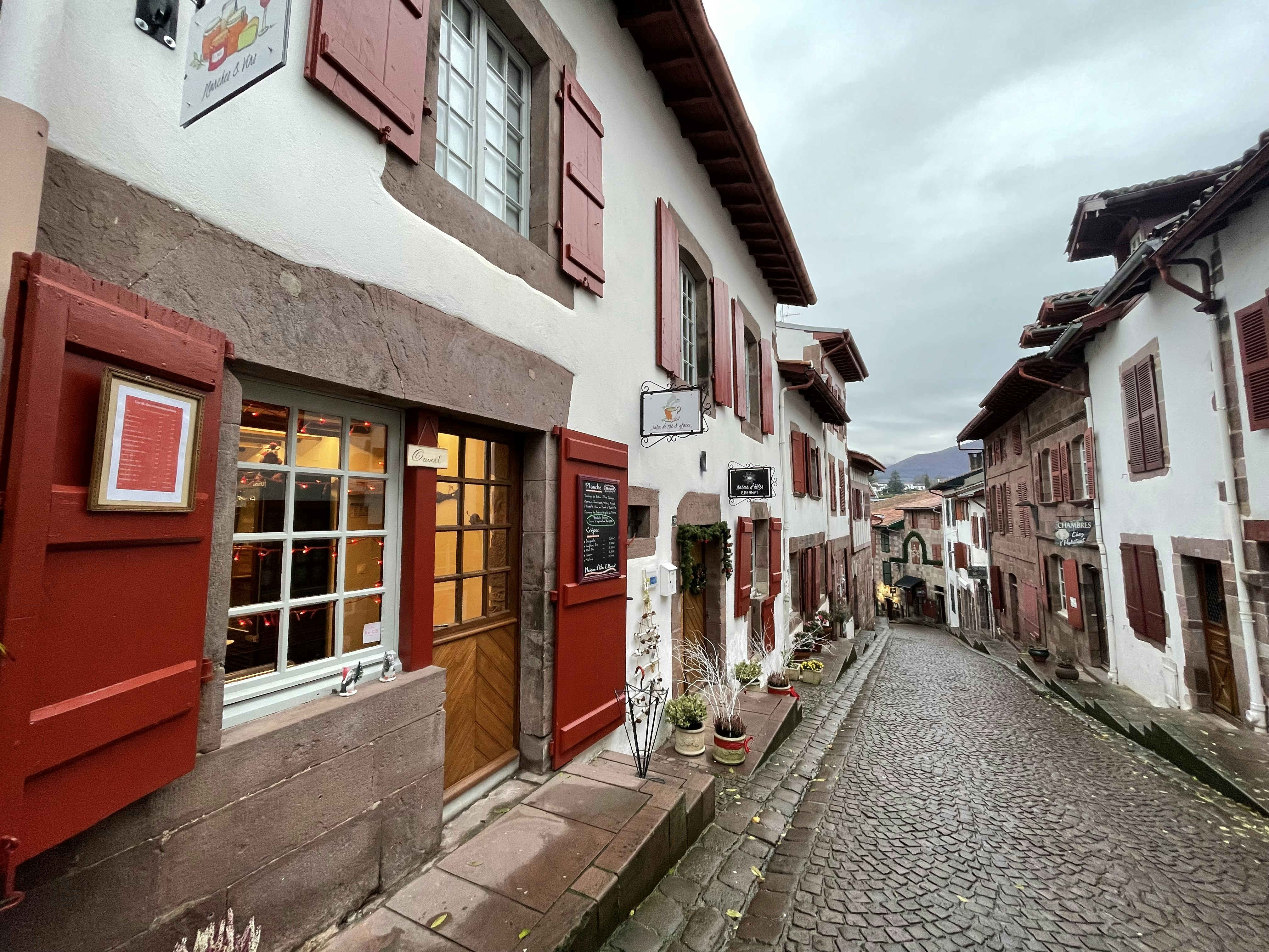 a cobblestone street with red shutters and windows