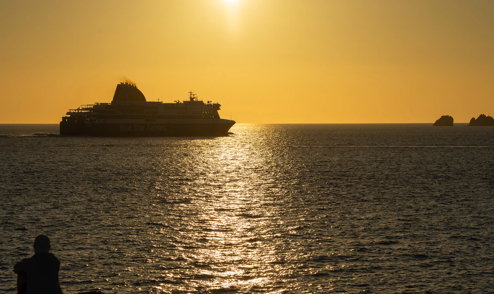 A Greek ferry silhouetted on a golden sea at sunset, the kind of crossing island hoppers plan with a Greece eSIM