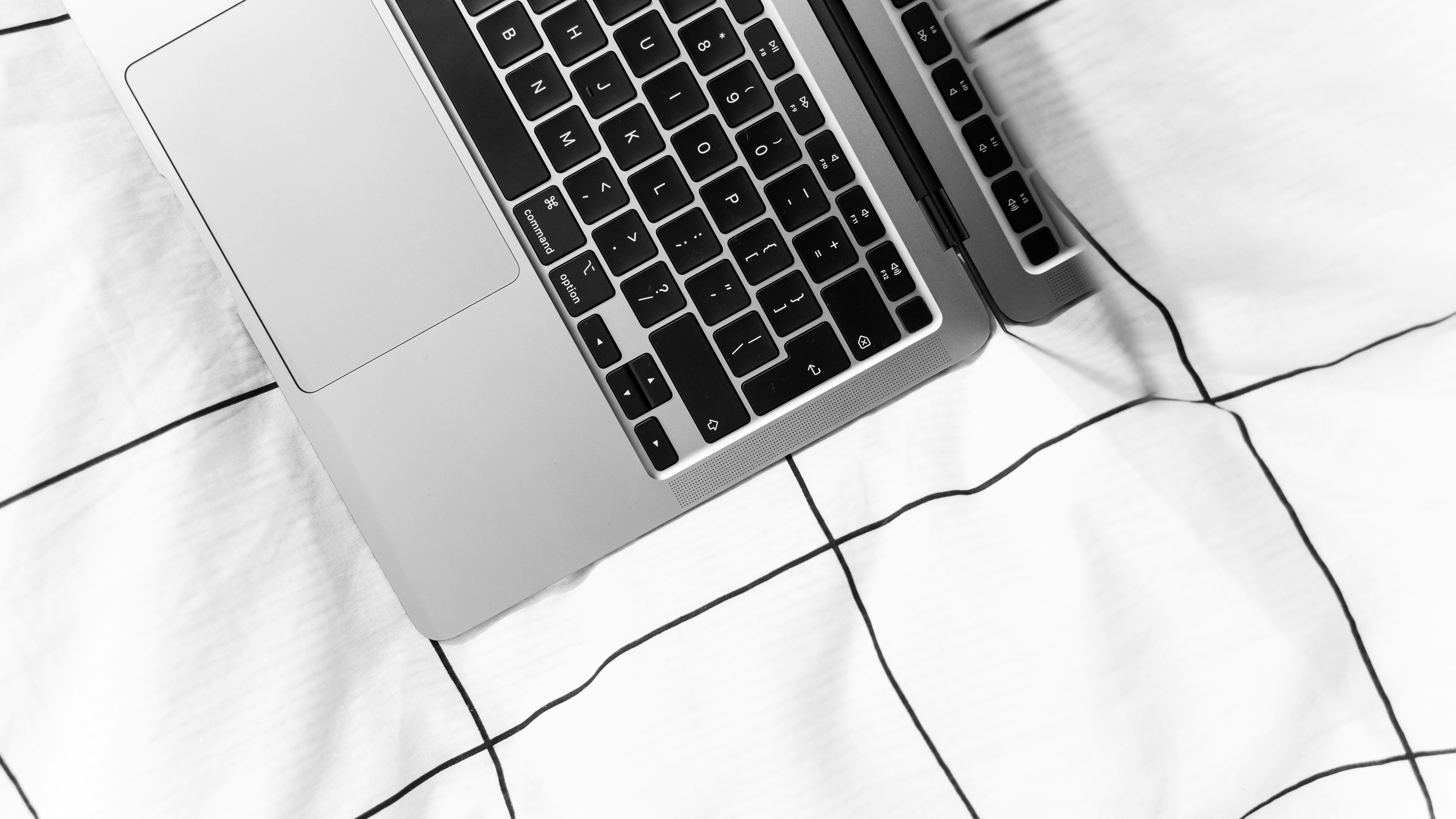 two laptop computers sitting on top of a bed